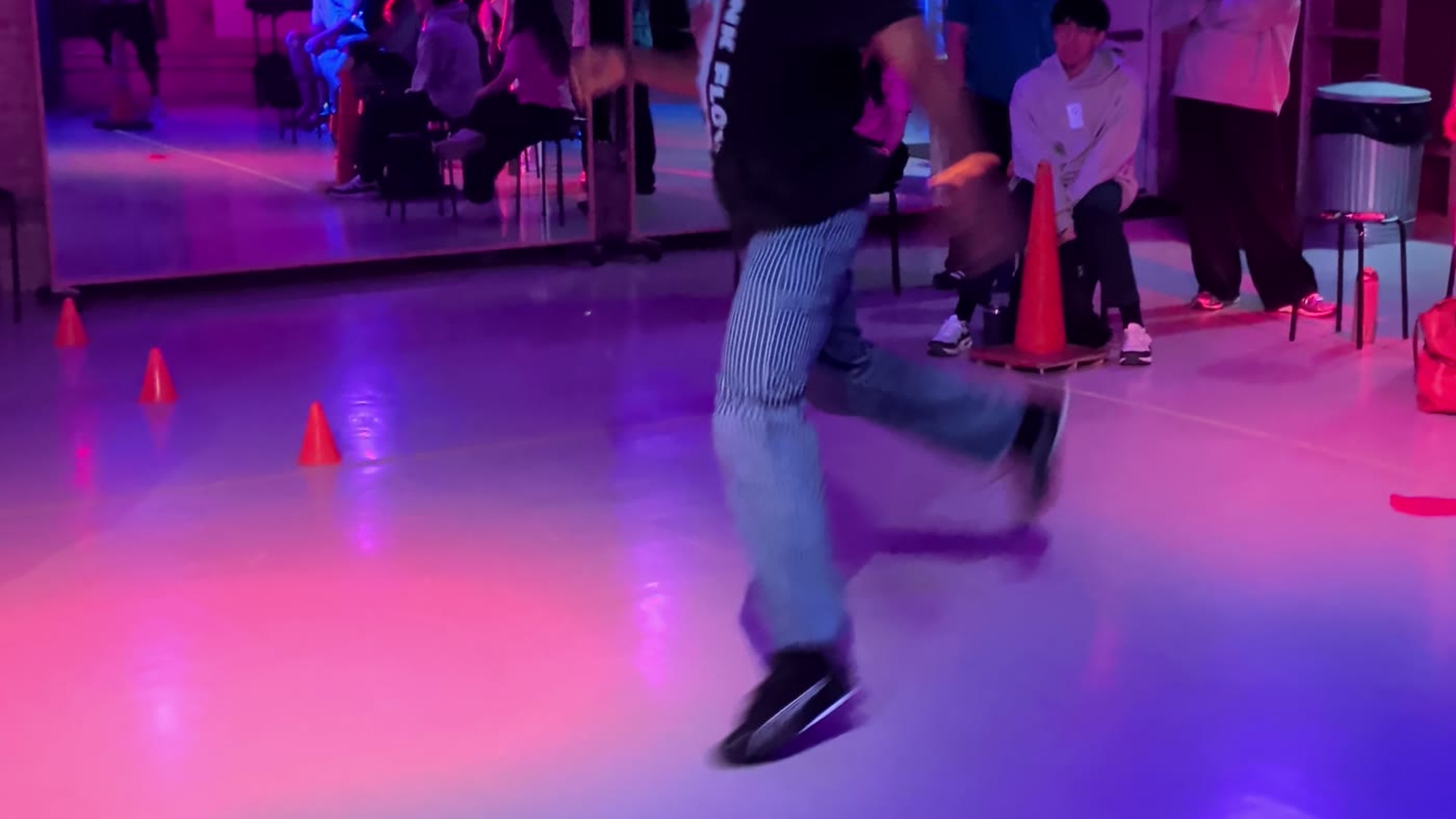 Dancer mid-battle under purple lights at Danzversity