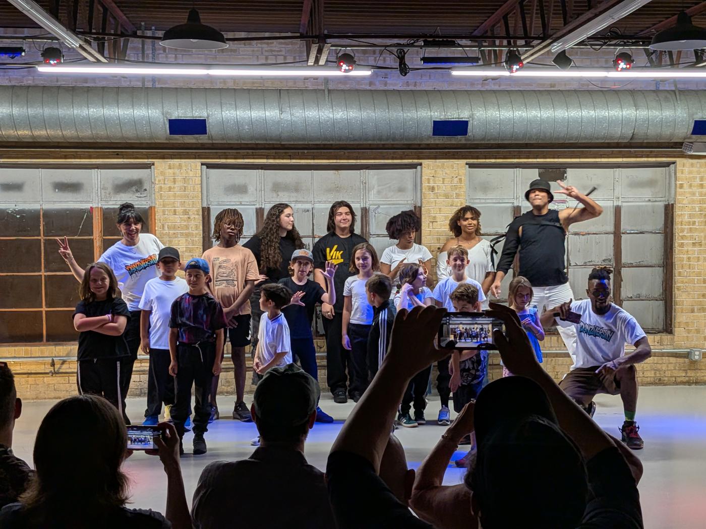 Youth crew lined up on the floor as families film on their phones